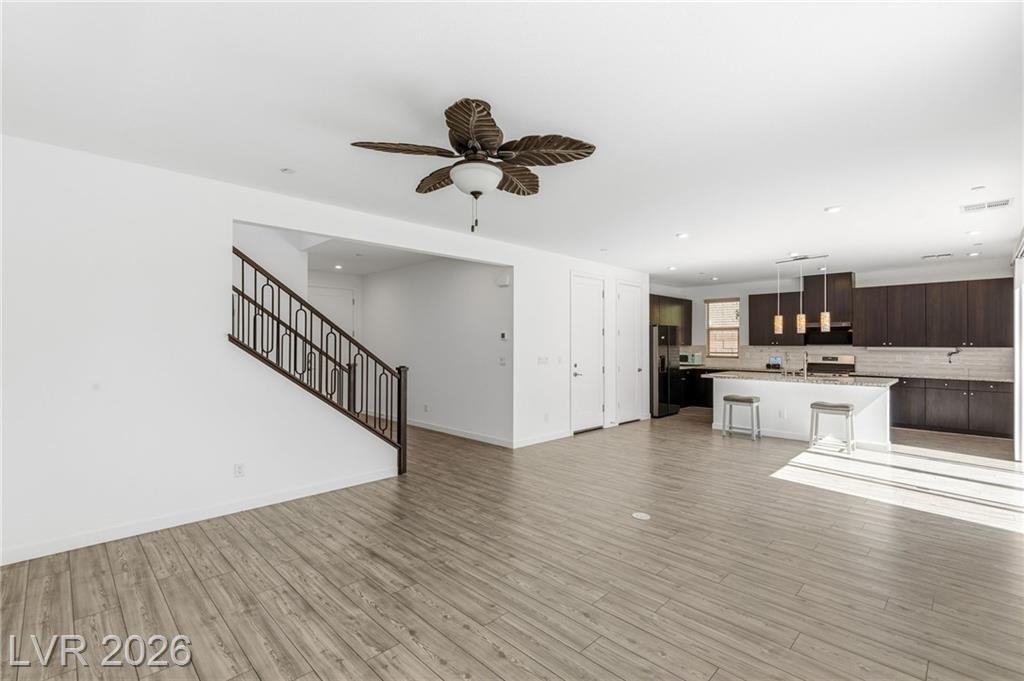 Open great room at 3233 Waterstone Avenue with wood-look tile, ceiling fan and a view to the kitchen