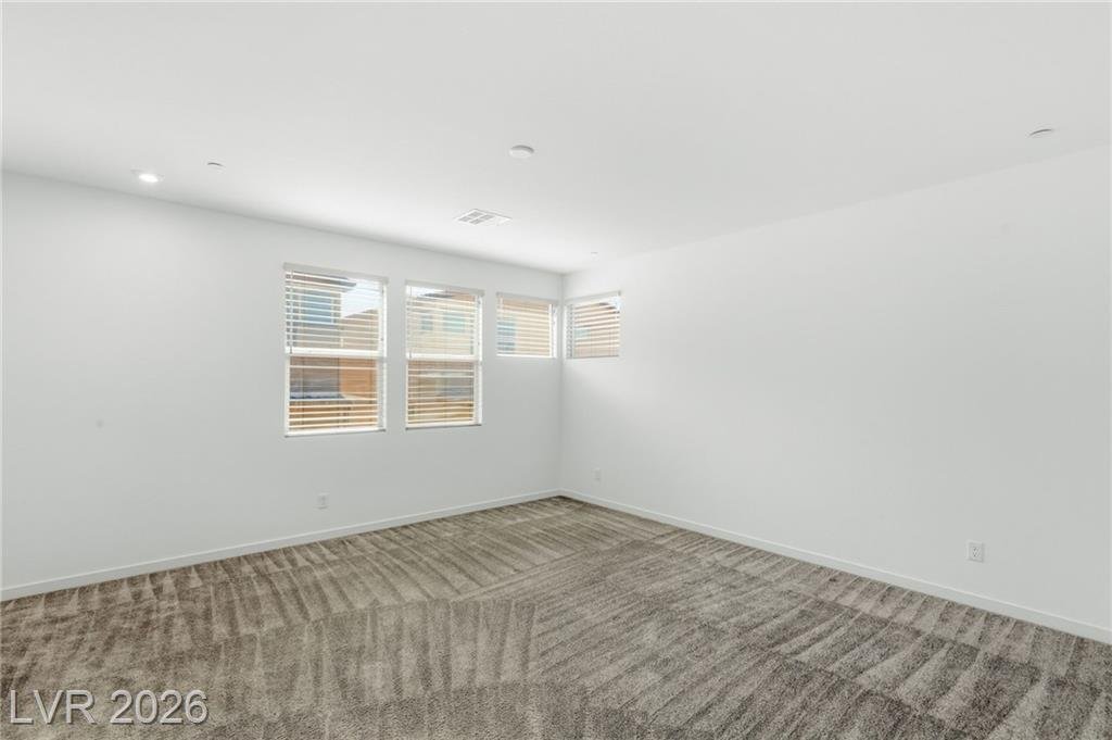 Primary bedroom at 3233 Waterstone Avenue with a bank of windows and carpet