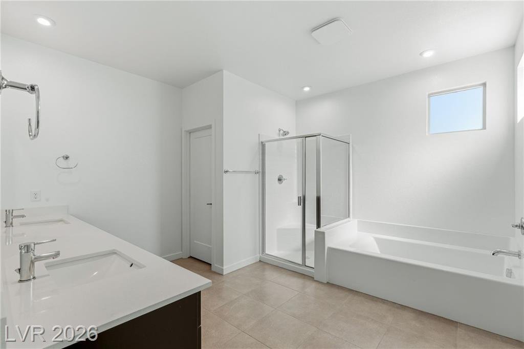 Primary bath at 3233 Waterstone Avenue with dual vanity, soaking tub and glass shower