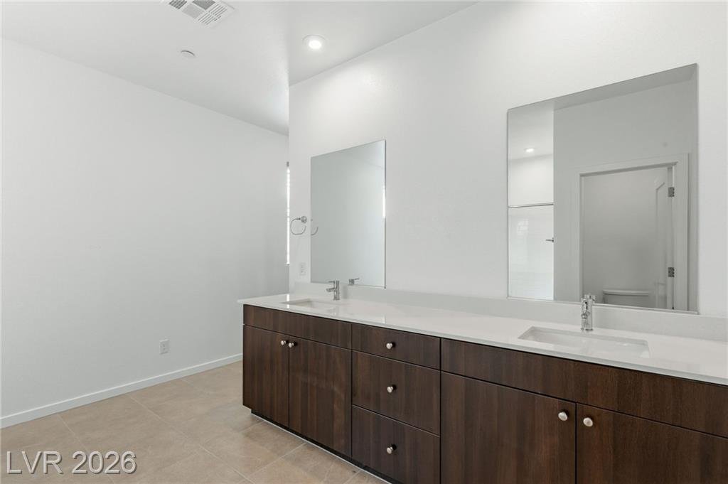 Primary bath double vanity with a wide mirror and espresso cabinets