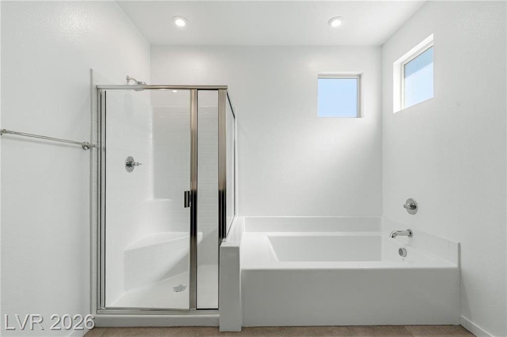 Glass-enclosed shower next to a separate soaking tub
