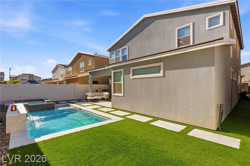 Pool running along the side of the house with artificial turf and stepping pavers