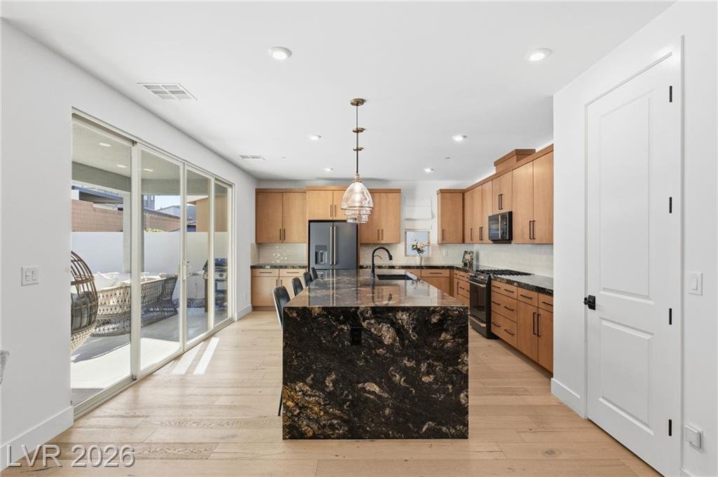 Kitchen with a dark granite waterfall island and sliding doors to the covered patio