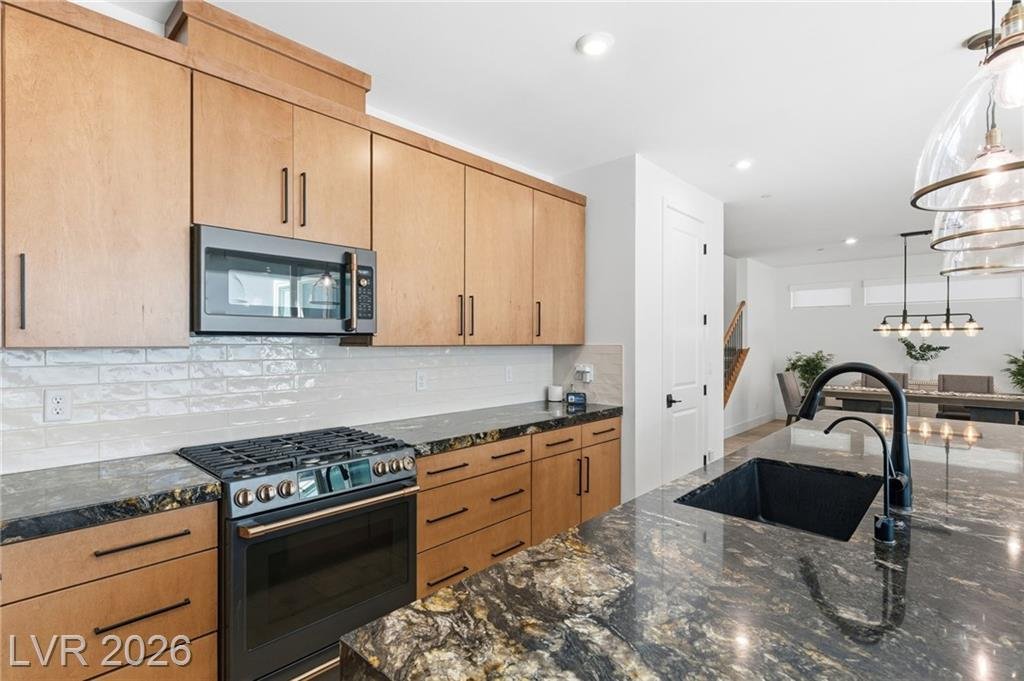 Café Series black stainless gas range with bronze hardware and white tile backsplash