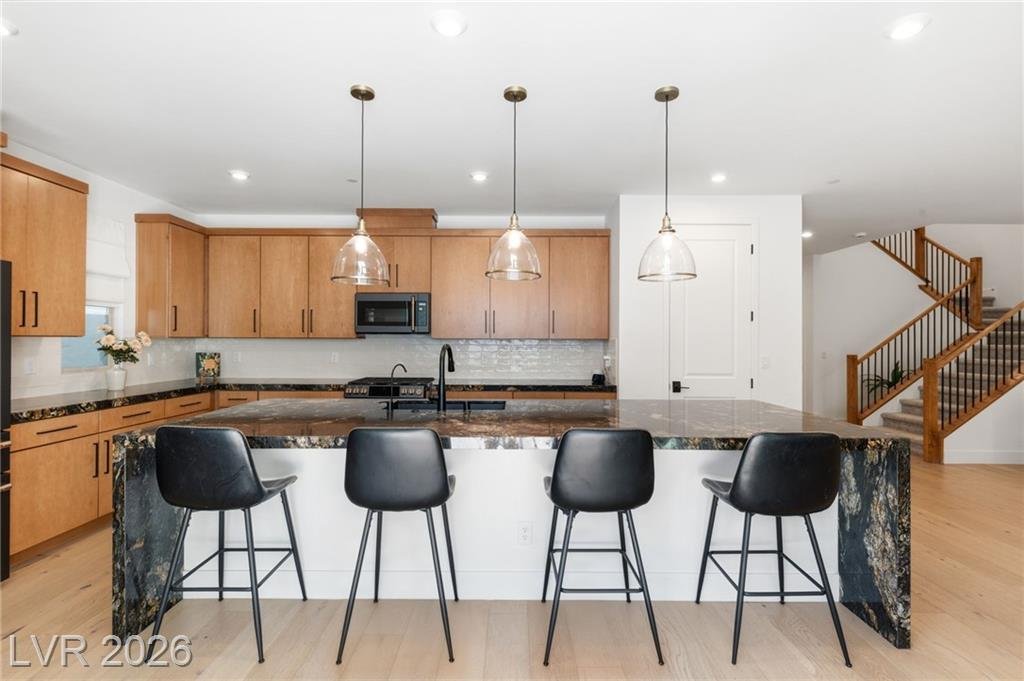 Island seating for four under glass pendants with the staircase beyond