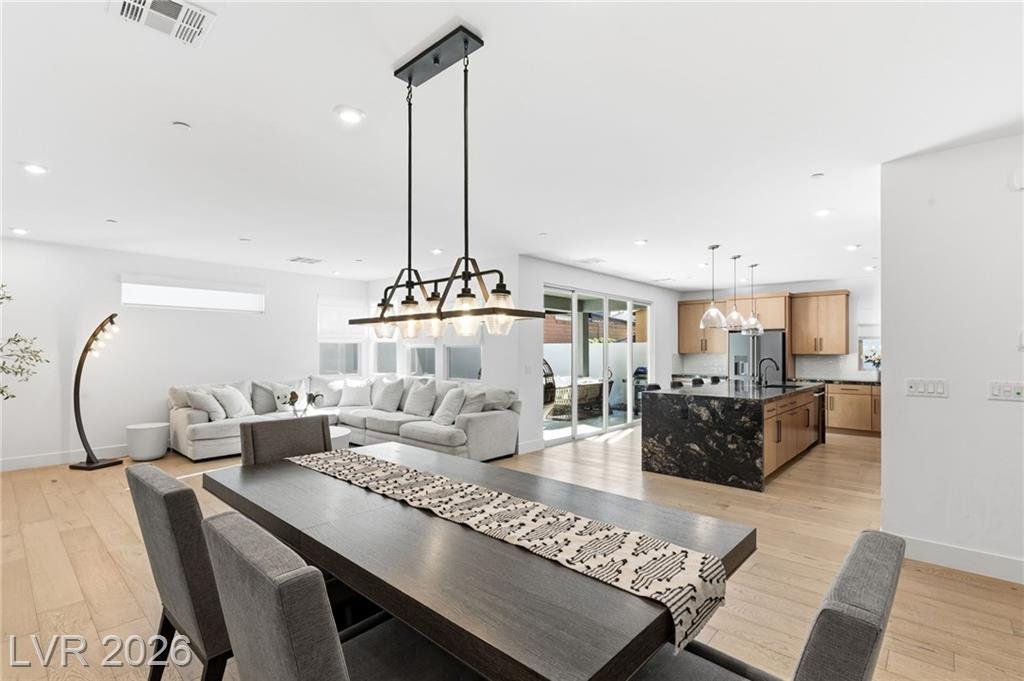 Great room looking across the dining table to the kitchen island and patio sliders