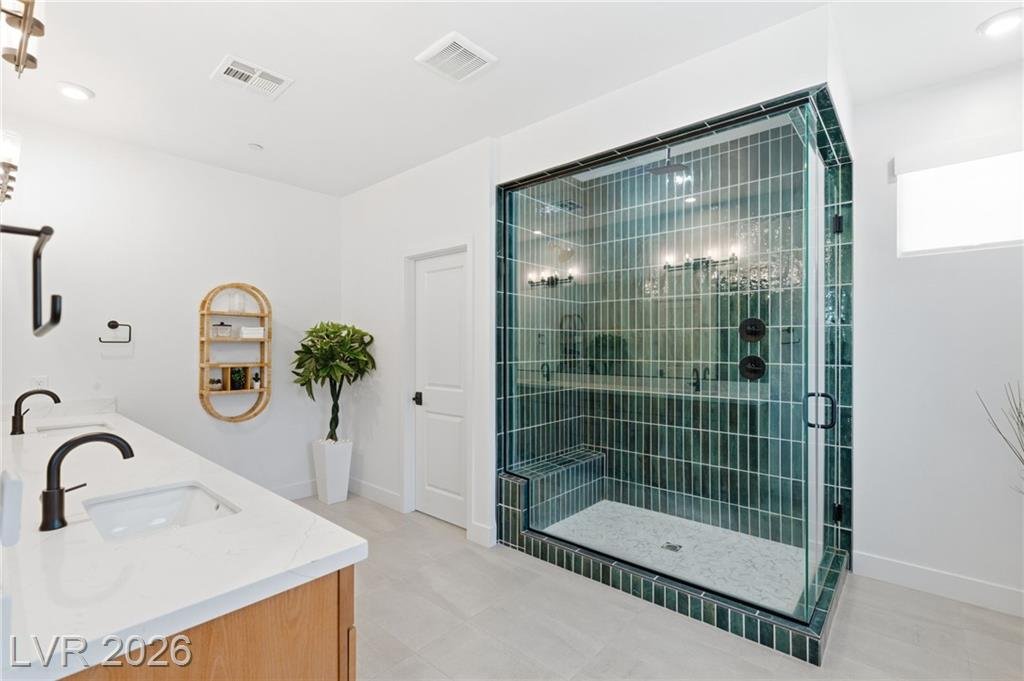 Glass-enclosed walk-in shower with emerald green tile in the primary bath at 3263 Fountaintree Avenue