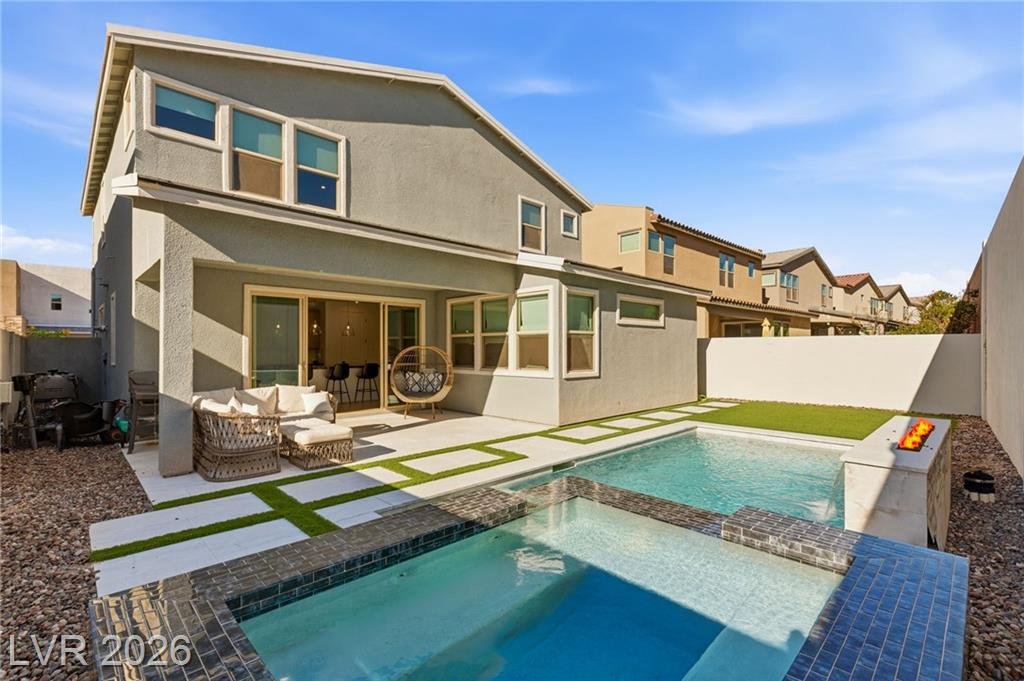 Back of the home with covered patio, tiled spa and pool
