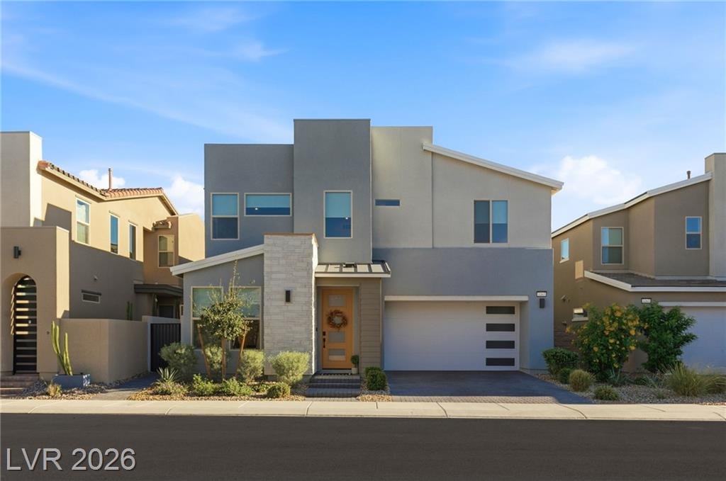 Straight-on street view of the home with wood front door and modern garage door