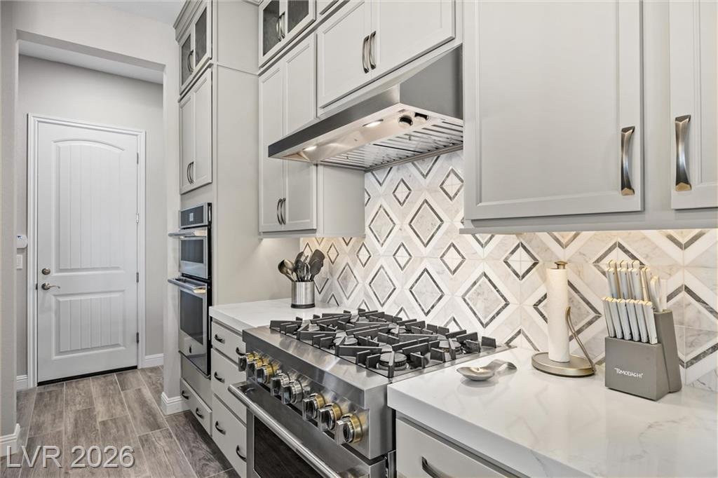 Gas range with a stainless hood and geometric tile backsplash