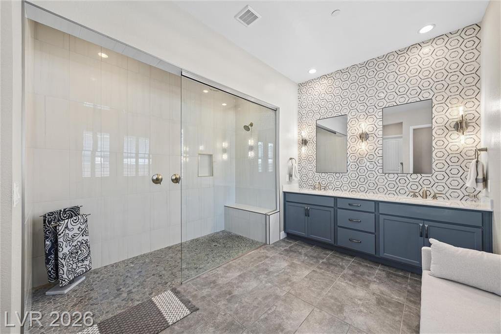 Oversized glass walk-in shower with a pebble floor