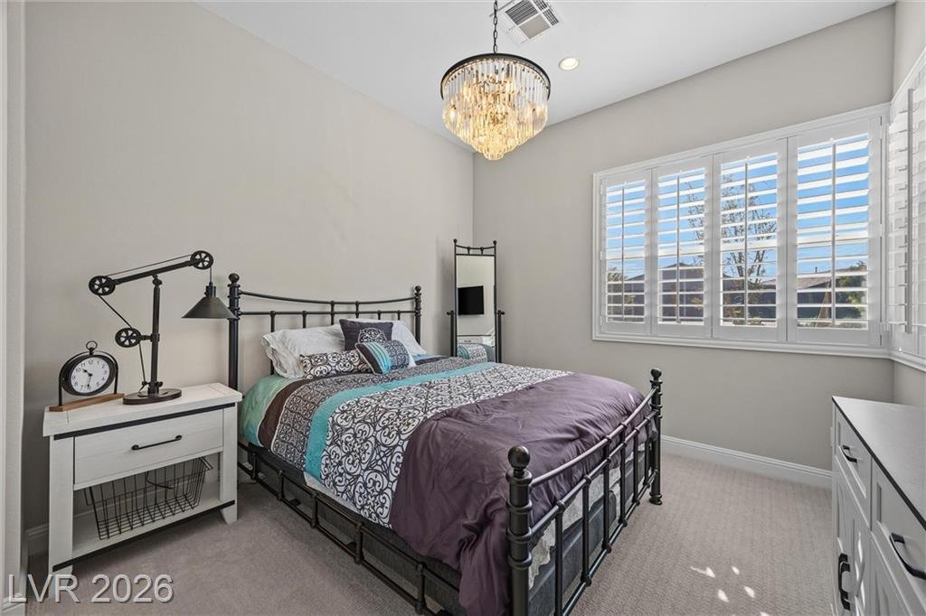 Second bedroom with plantation shutters and a crystal chandelier