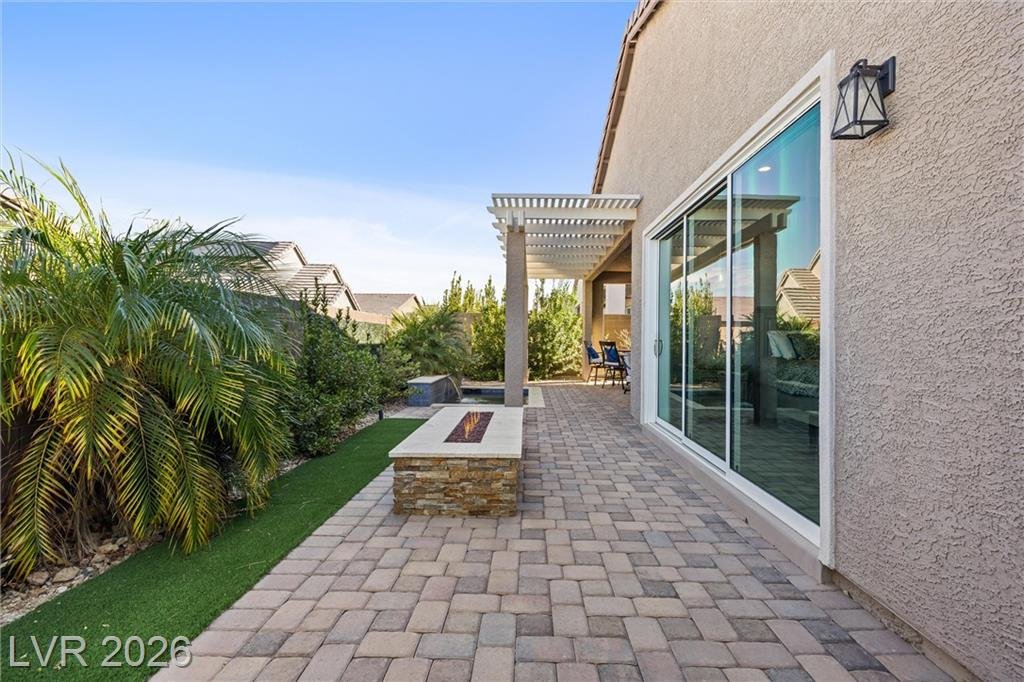 Paver side yard with a pergola and a gas fire pit