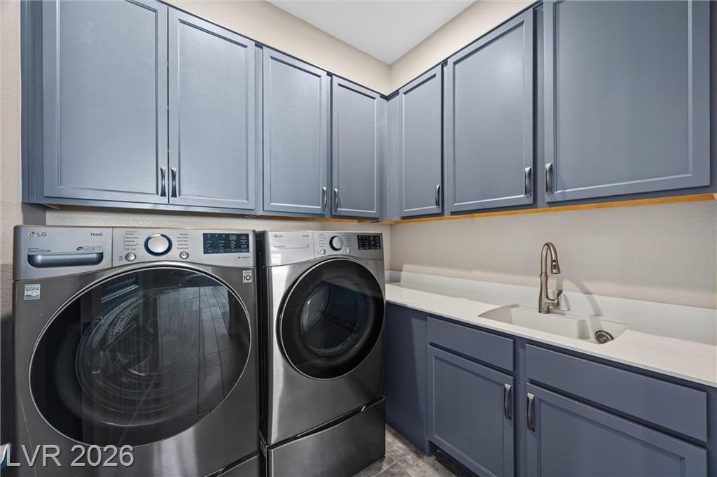 Laundry room with gray cabinets, sink and front-load washer and dryer