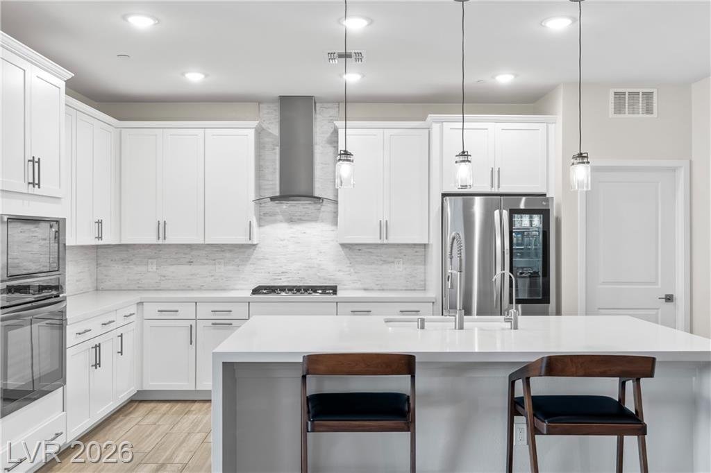 White shaker kitchen at 3500 Brezine Avenue with a stainless wall oven and microwave