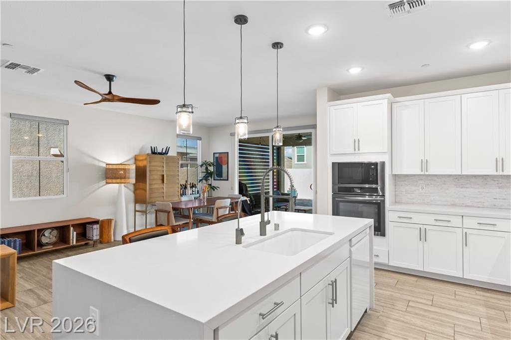 Island with undermount sink and white cabinets toward the dining area