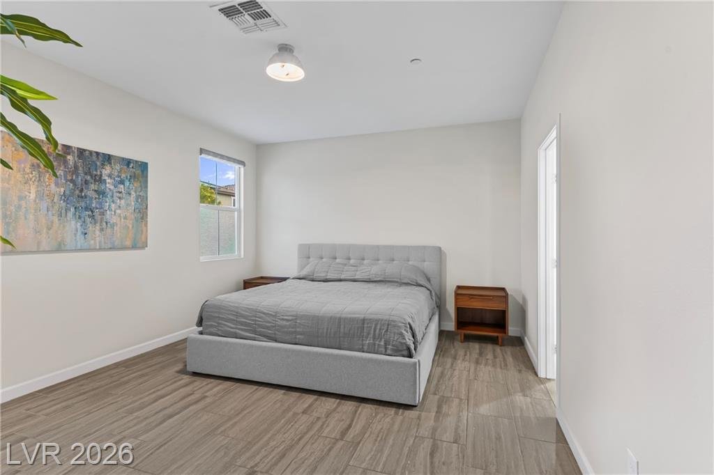 Bedroom with wood-look tile floors and a side window