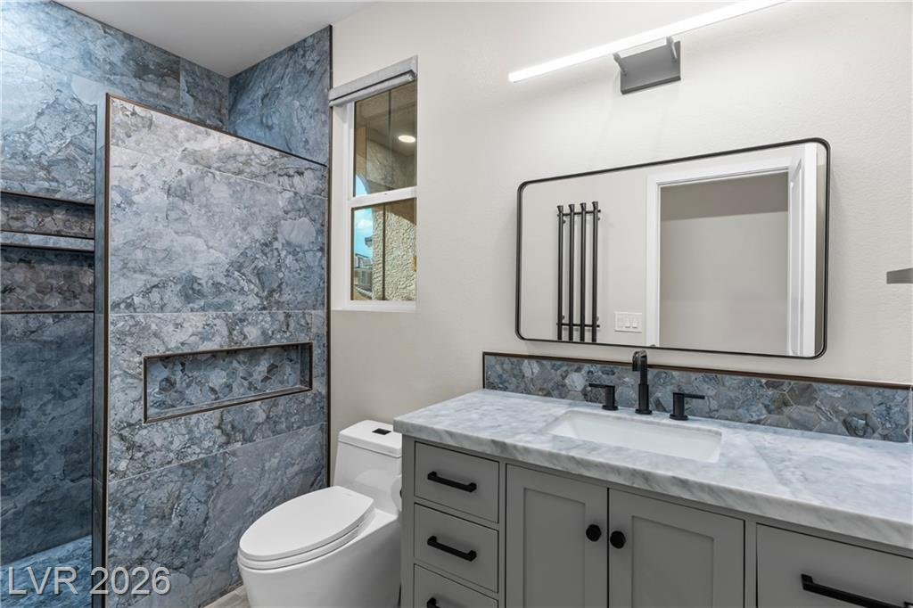 Renovated hall bath with stone tile and a black-framed mirror