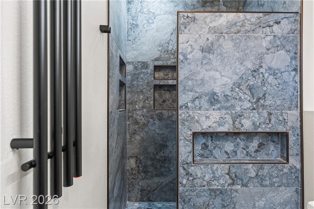 Walk-in stone shower with a built-in niche and matte black fixtures