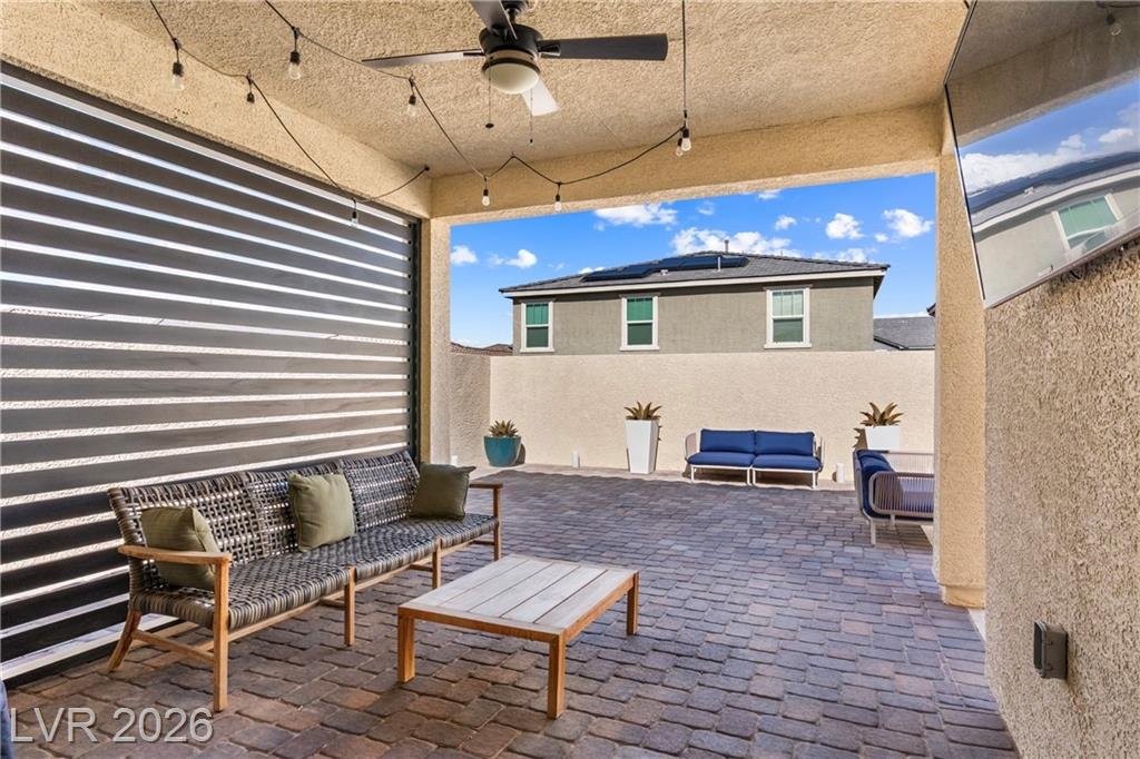 Covered patio with string lights, a ceiling fan and an aluminum privacy screen