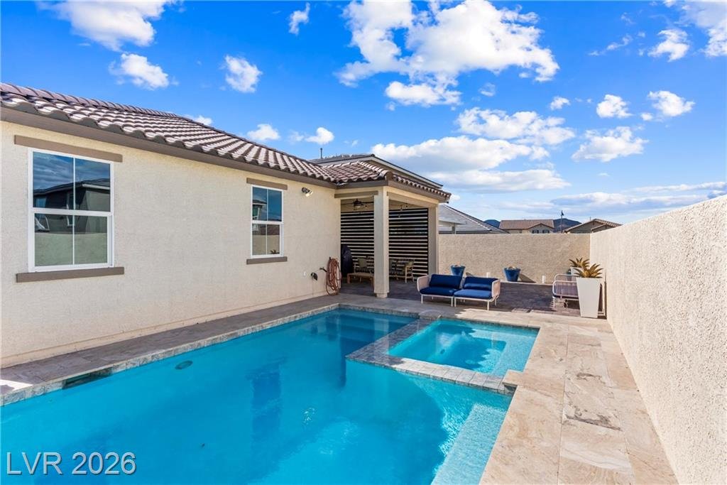 Heated pool with spillover spa and natural stone deck in Inspirada